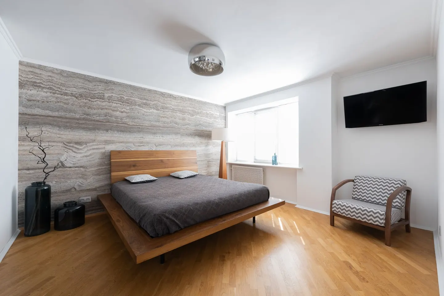 Bedroom with a low platform bed, wood floor and a bright window