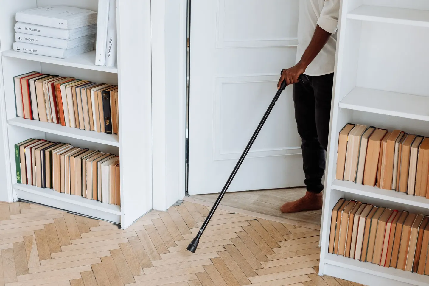 Person walking with a cane through a doorway at home