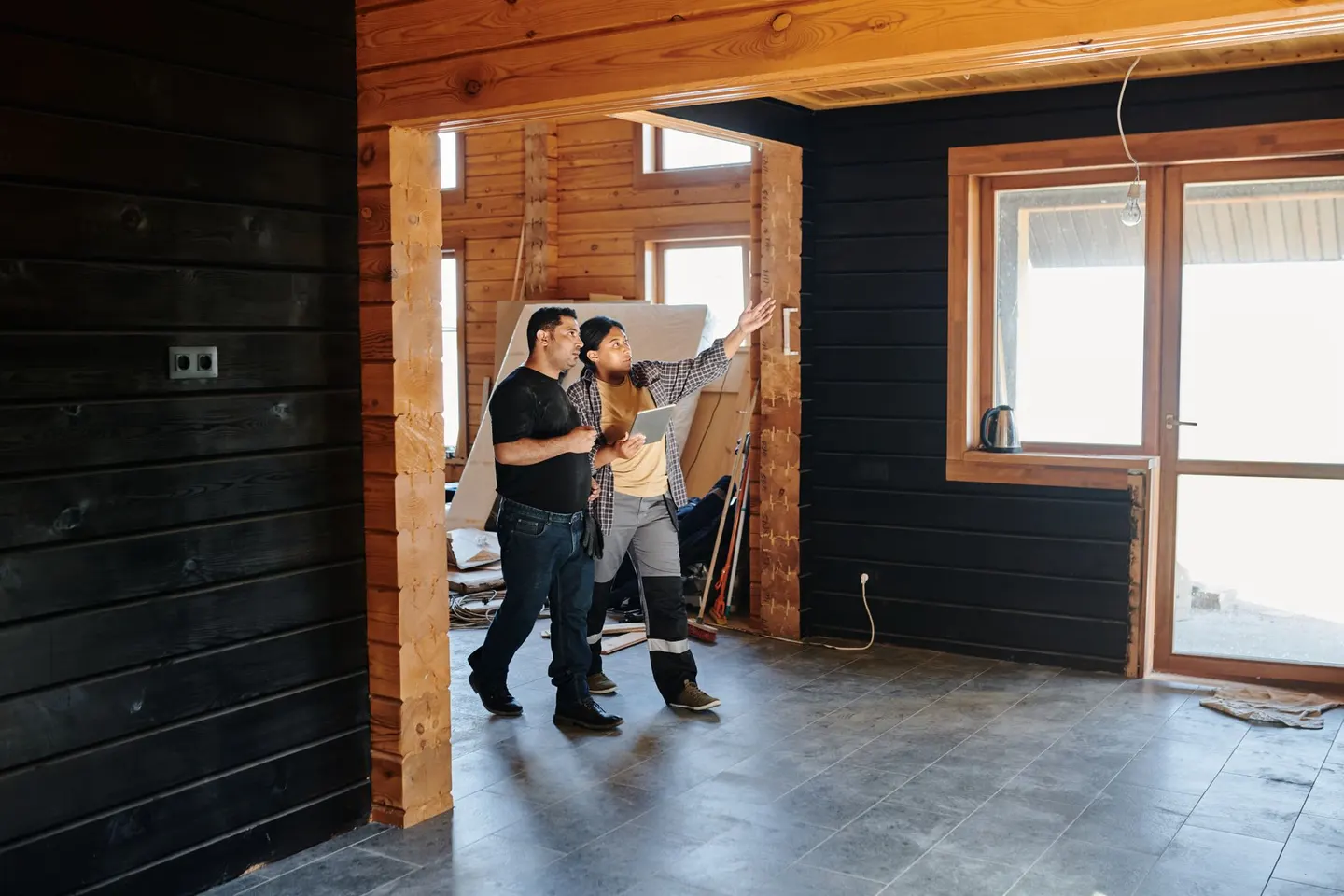 A contractor and a homeowner talking inside a house under renovation
