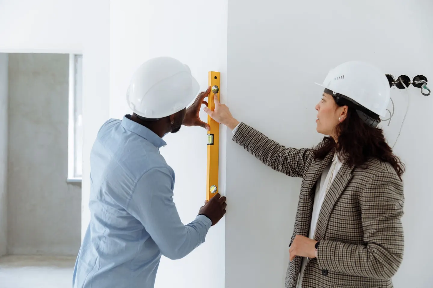 Two contractors checking a wall with a level