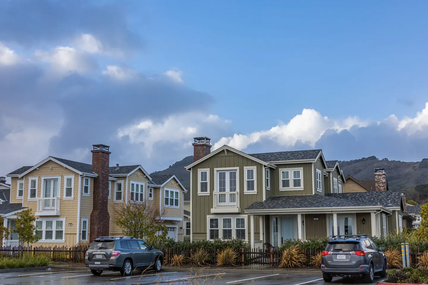 Two-story houses on a suburban street with hills behind