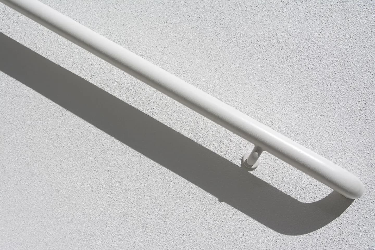 White handrail mounted along a textured wall