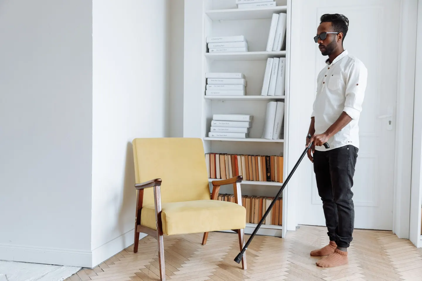 A man with a walking stick standing in a bright room