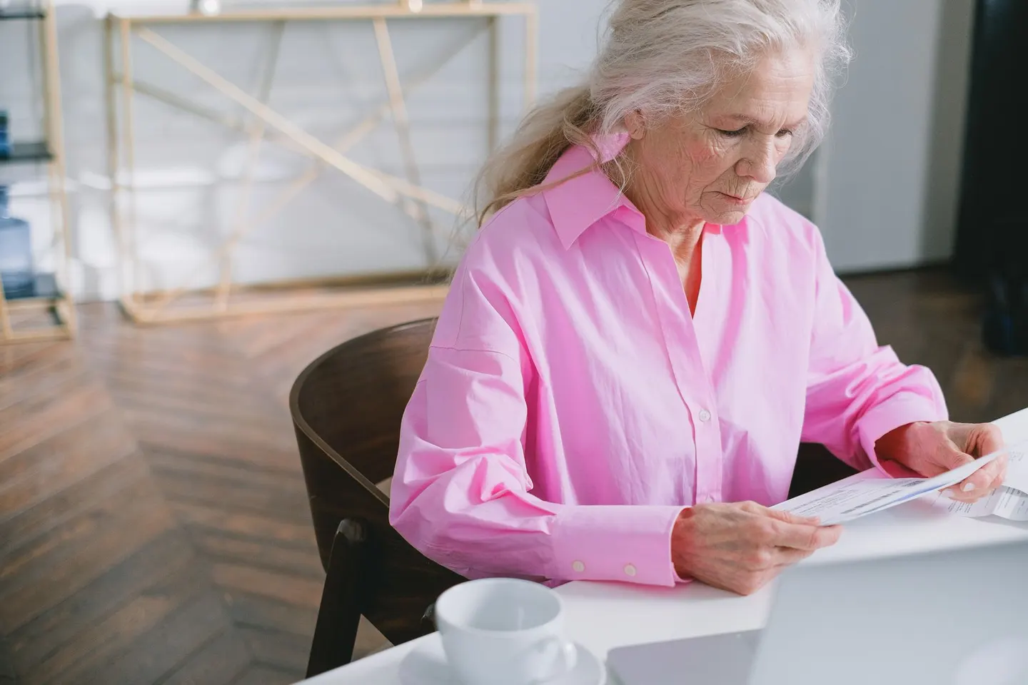 Older woman reading papers at a desk at home