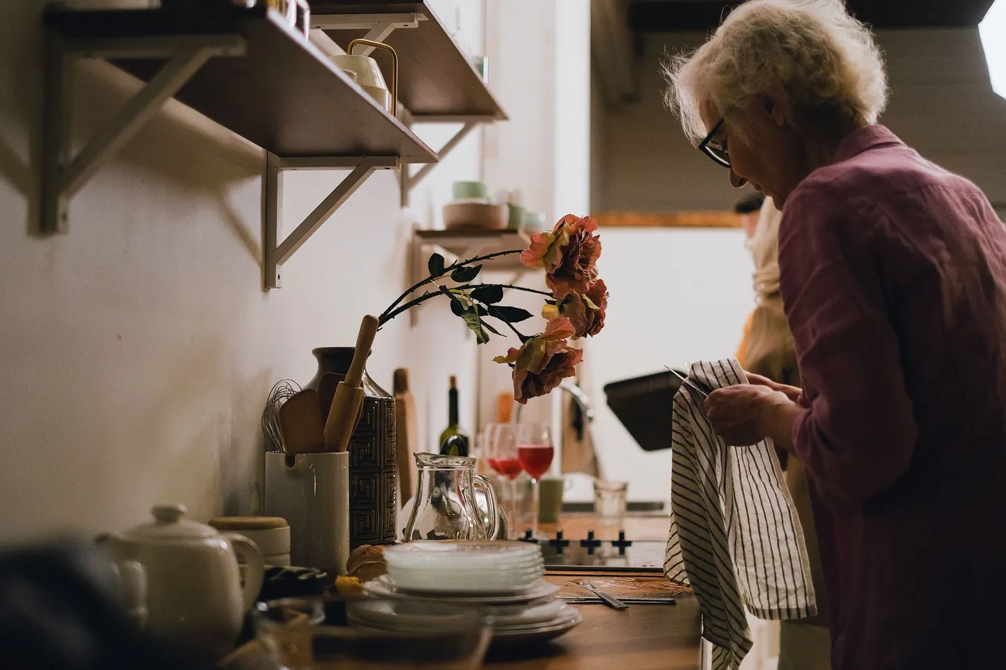 Older woman drying dishes in her kitchen