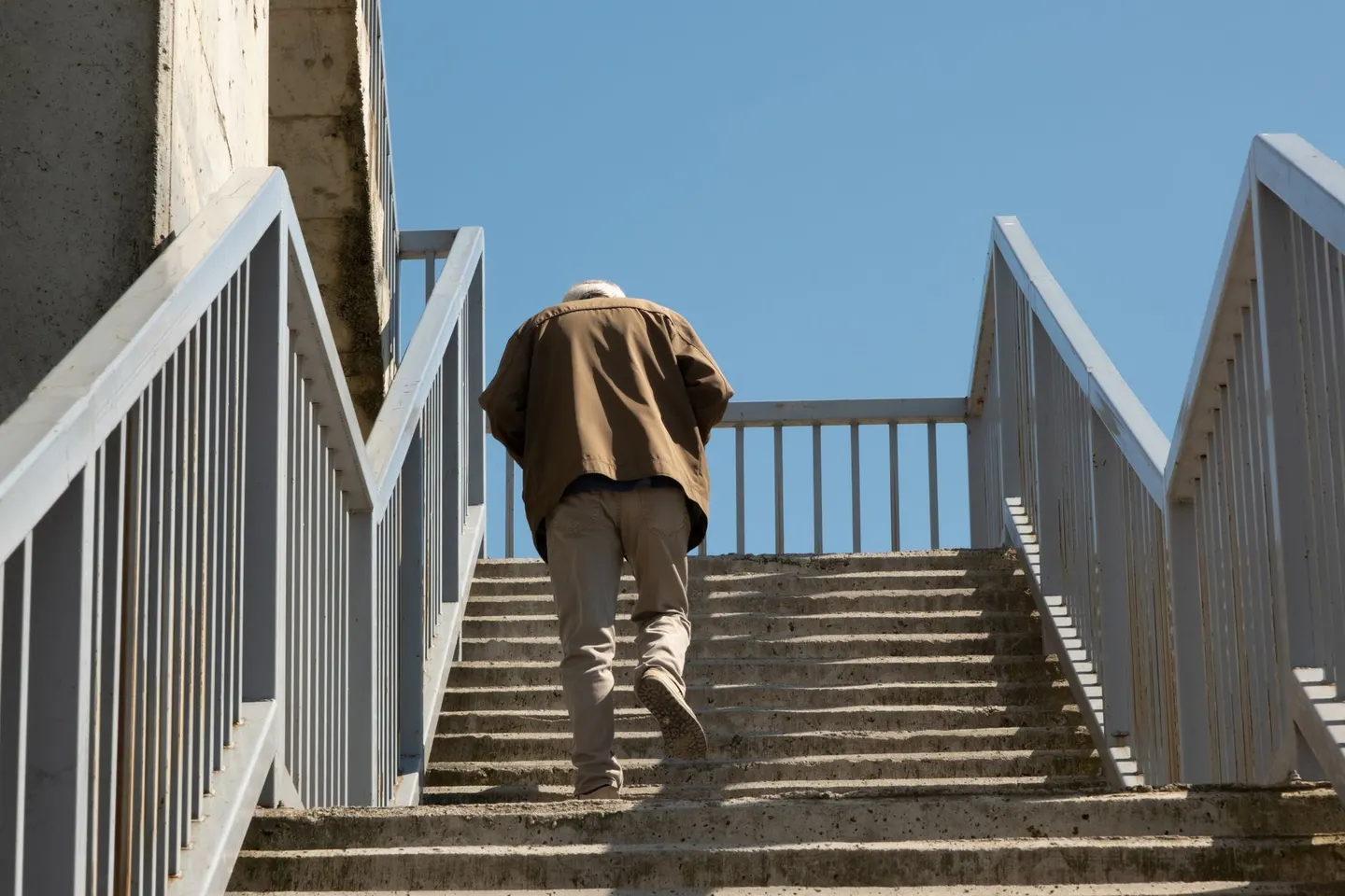An older man climbing concrete steps outside