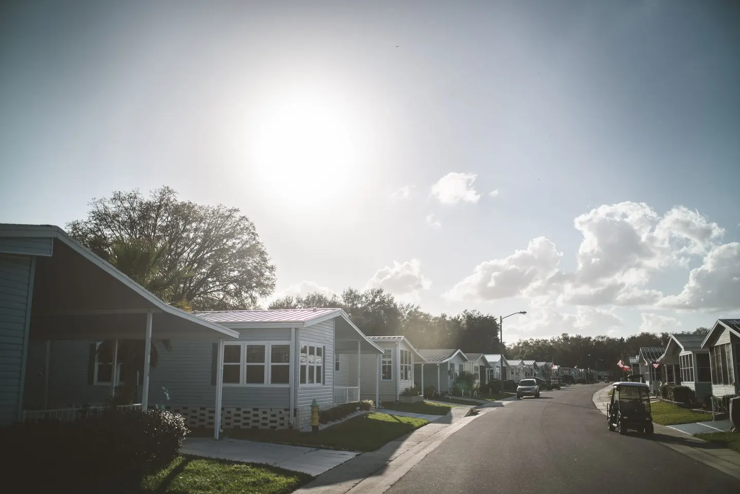A quiet street of single-story homes with a golf cart parked at the curb