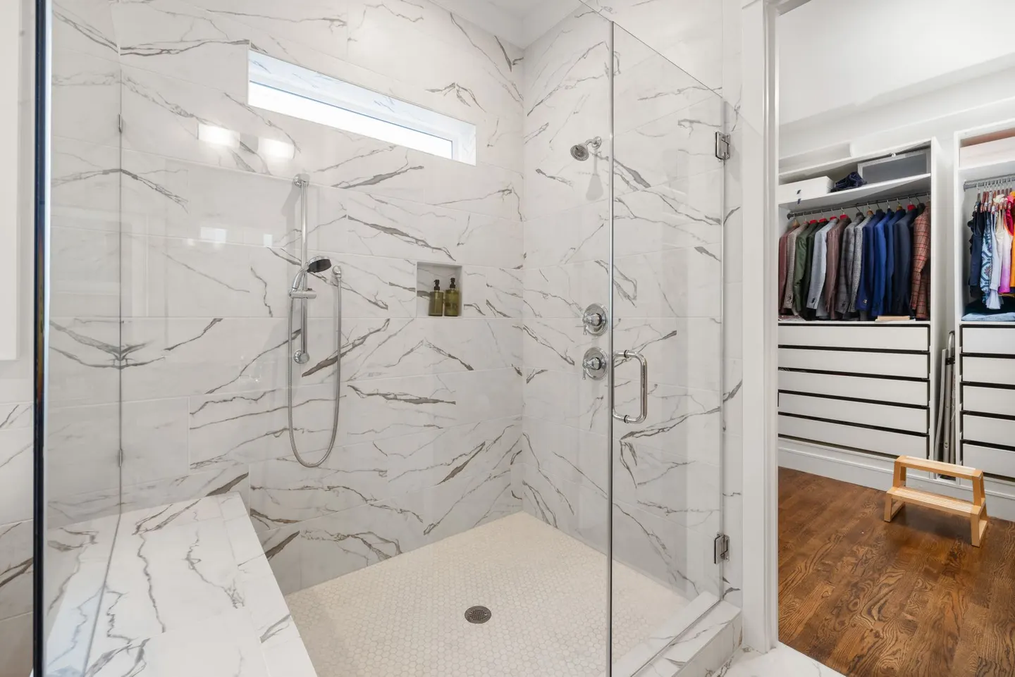 Tiled walk-in shower with a built-in bench, hand-held shower head and glass door