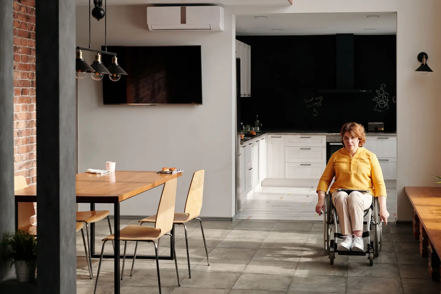 A woman in a wheelchair sits in a modern kitchen, showcasing accessibility in home design
